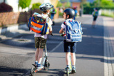 Kids wearing helmets on scooters in pedestrian zone