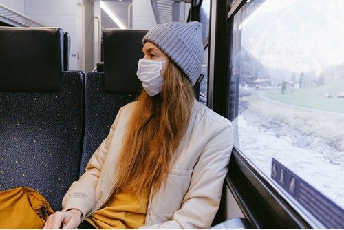 Female passenger on a train wearing a white face mask